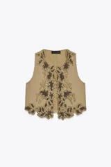 Chaleco color arena con bordados florales en hilo dorado y cuentas negras.