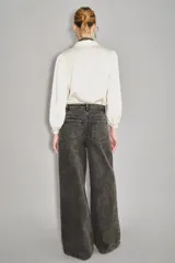 Pantalón de denim de corte ancho y tiro alto, color negro lavado, con apliques bordados florales en tonos oscuros a lo largo de las piernas.