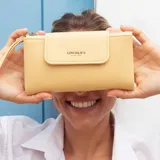 Billetera larga color camel, con textura símil cuero, cierre de broche en solapa frontal y correa de mano desmontable.