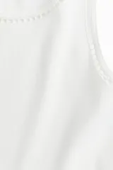 Musculosa cropped blanca de punto de algodón acanalado con corte ajustado e inserciones de encaje en escalera en escote y sisas.