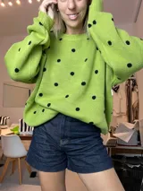 Suéter de tejido de punto color verde pistacho con diseño de lunares negros distribuidos por toda la prenda. Presenta cuello redondo y mangas largas abullonadas.