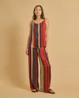 Top fluido con tirantes finos trenzados y escote barco, con estampado de rayas verticales rojas, azules y amarillas.