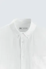 Camisa celeste a rayas verticales, de corte relaxed fit, confeccionada en lino y algodón. Tiene cuello abotonado, manga larga con puños abotonados, bolsillo de parche en el pecho y cierre frontal con botones.