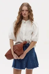 Camisa blanca de lino con cuello mao, cierre frontal con botones de nácar y mangas abullonadas hasta el codo.