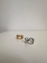 Anillo plateado de acero quirúrgico hipoalergénico con diseño irregular y aberturas circulares.