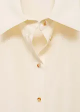 Camisa verde esmeralda de corte recto, con cuello camisero, mangas cortas y cierre frontal con botones.