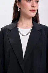 Blazer negro de lyocel con solapas clásicas, corte recto y bolsillos delanteros.