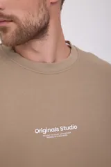 Buzo color arena de manga larga y cuello redondo, con logo "Originals Studio" estampado en el pecho.