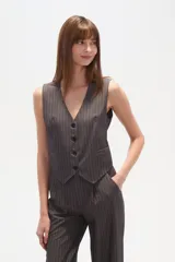 Chaleco de vestir sin mangas, color negro con finas rayas verticales blancas. Presenta escote en V, cierre frontal con botones y bolsillos falsos a la altura de la cintura.