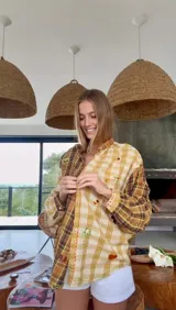 Camisa a cuadros en tonos tierra con apliques decorativos.