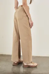 Pantalón wide leg color beige, de tiro alto, ligeramente ajustado en cintura y con ruedo desflecado.