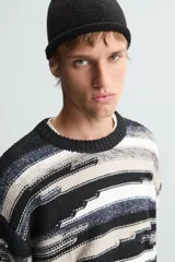 Sweater de punto con cuello redondo y manga larga, con diseño de rayas horizontales en tonos negro, gris y blanco.
