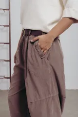 Pantalón de corte amplio color marrón, con cintura elastizada, detalle de botones en los laterales y cinturón incluido.