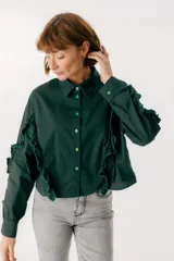 Camisa celeste con cuello clásico, cierre frontal con botones y mangas largas con volados.
