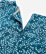 Vestido corto de crepé color verde azulado con estampado de mini corazones blancos, escote en pico, mangas largas con puños elásticos y cierre en la espalda.