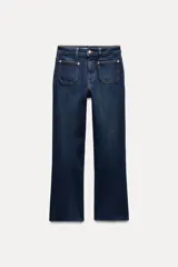 Pantalón de jean azul oscuro, de tiro alto, corte mini flare y largo cropped. Tiene bolsillos de parche delanteros y traseros, y cierre frontal con cremallera y botón metálico.