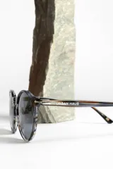 Lentes de sol unisex con montura redonda negra y lentes degradadas de gris a transparente.