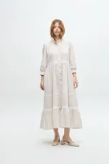 Vestido camisero midi color beige a rayas verticales, con cuello mao, mangas 3/4 abullonadas y festones de algodón en el cuerpo. Cierre frontal con botones.