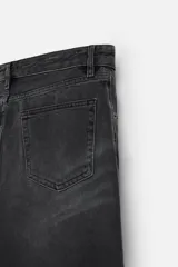 Pantalón de jean negro con efecto lavado, corte flare, cinco bolsillos, cierre frontal con cremallera y botón, y bajo con acabado irregular.