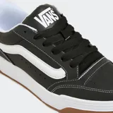 Championes Vans Hylane negros con detalles en blanco y suela marrón. Inspirados en el skate Y2K, reinterpretan la silueta Upland de 1999. Cuentan con Sidestripe brillante en 3D, logotipos bordados, lengüeta de skate abultada, construcción de suela de copa y textura única de V entrelazada.