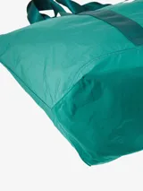 Bolso tote negro de Carhartt WIP, modelo Canby. Confeccionado en tafetán de nailon ligero, con compartimento principal con cierre de botón a presión, bolsillo interior con cremallera y bolsillo exterior. Asas de cincha resistentes y etiqueta cuadrada de Carhartt.