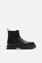 Bota Chelsea de cuero negro con elásticos laterales, tirador trasero y suela track.