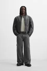 Pantalón gris oscuro de corte amplio, con bolsillos frontales y traseros de parche. Incluye un bolsillo lateral con cierre de cremallera.