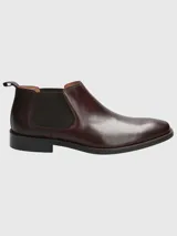Bota Chelsea de cuero negro con elásticos laterales y suela plana.