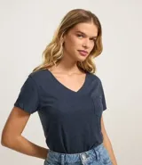 Blusa blanca de algodón con cuello en V, manga corta y bolsillo frontal.