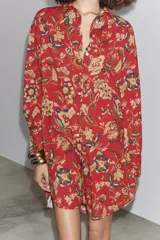 Camisa larga de algodón con estampado floral en tonos rojos, marrones y verdes. Tiene cuello solapa, manga larga con puños y bajo redondeado.