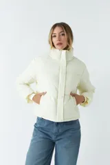 Campera corta color crema con cuello alto y cierre frontal con botones a presión.