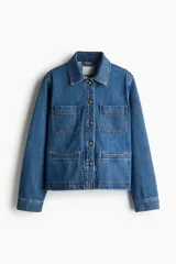 Campera azul de denim con cuello clásico, cierre frontal con botones dorados, dos bolsillos de parche en el pecho y dos bolsillos ribeteados en la cintura.