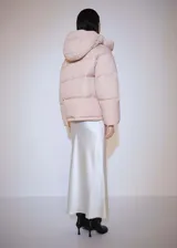 Campera puffer color rosa pálido con capucha, cierre frontal con botones a presión y bolsillos laterales.
