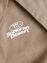 Remera color arena con estampado en el centro de la espalda con la inscripción "Sonoran Desert" en amarillo.