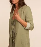 Blazer largo color beige confeccionado en viscosa y lino, con cuello solapa, bolsillos y forro estampado a rayas.