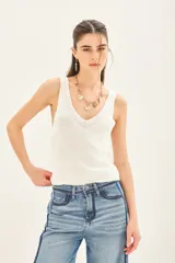 Musculosa blanca tejida en hilado de algodón, con escote en V pronunciado y calce al cuerpo.