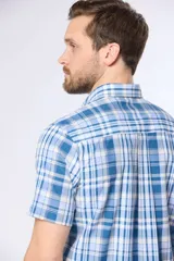 Camisa de manga corta con cuello abotonado y estampado a cuadros en tonos de azul y blanco. Hecha en Uruguay.