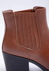 Bota negra de caña baja con pespuntes, tacón medio y diseño clásico.