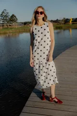 Vestido midi blanco con estampado de lunares negros, sin mangas y corte holgado.