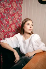 Blusa blanca de algodón con mangas 3/4 abullonadas y volados en los hombros.