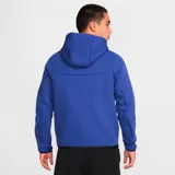 Campera deportiva Nike Tech Fleece color azul con cierre frontal, capucha y detalles en negro. Incluye logo de Nike bordado en el pecho y bolsillo con cierre en la manga izquierda.