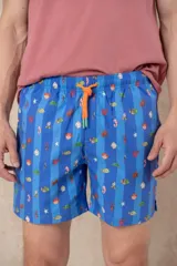 Short de baño azul vibrante con estampado repetitivo de cruces pequeñas en blanco y rojo. Presenta cintura elástica fruncida y cordón de ajuste trenzado en color coral con puntas de neón verde lima.