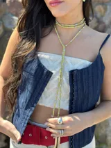 Collar amarillo con tres tiras de cuero sintético y cuentas plateadas.