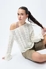 Sweater calado color crudo, de mangas largas acampanadas y escote amplio.