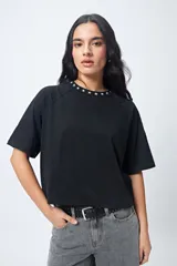 Remera negra de corte holgado con mangas ranglan y cuello redondo con bordado de estrellas blancas.