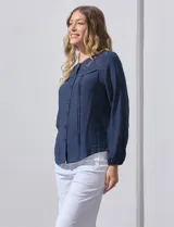 Blusa blanca de manga larga con cuello redondo y detalle de broderie en el canesú.