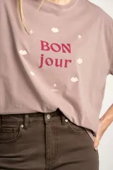 Remera color lila con estampa frontal de la frase 'Bon jour' con estrellas y labios.