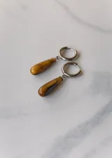 Aros colgantes de acero quirúrgico hipoalergénico con dije de piedra natural en forma de gota color azul oscuro.