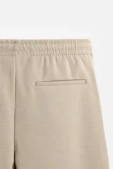 Pantalón negro de corte cropped, con cintura elástica ajustable con cordón, bolsillos laterales y traseros de vivo. El bajo tiene terminación con vuelta.