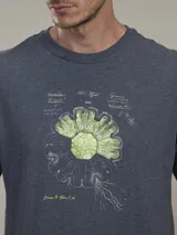 Remera celeste con estampado de un diseño floral en azul y texto en la parte inferior.